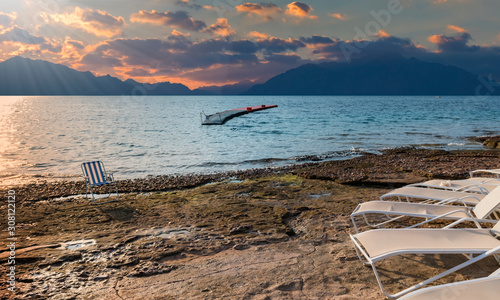 Sunset on stone beach near a coral reef and pier for water sport activities