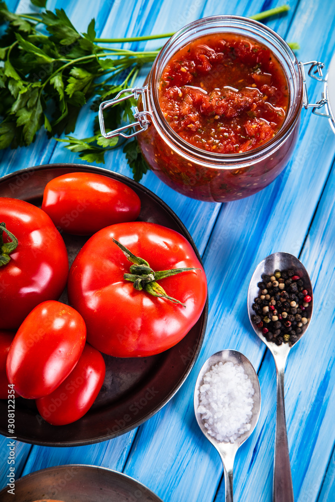 Raw tomatoes and tomato sauce in jar on wooden background Raw tomatoes and tomato sauce in jar on wooden background