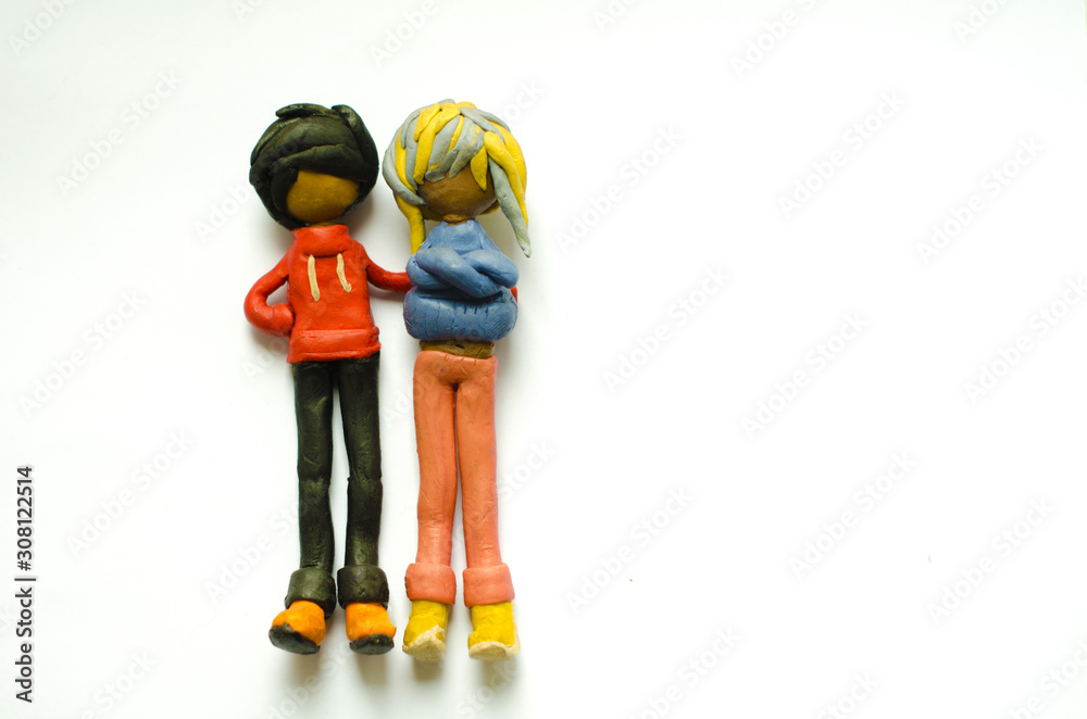 Plasticine figurines guy and girl on a white background. The guy put his hand on the shoulder of the girl. Right place for copyspace Plasticine figurines guy and girl on a white background. The guy put his hand on the shoulder of the girl. Right place for copyspace