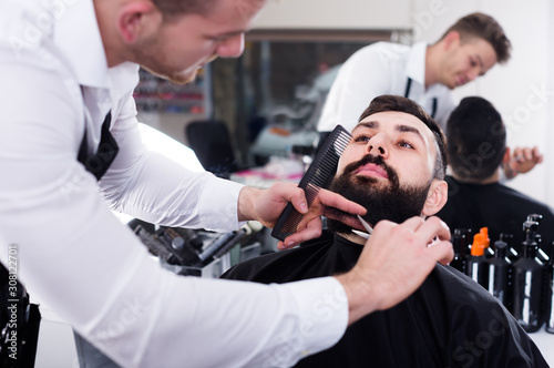 Adult guy creating shape for beard of client