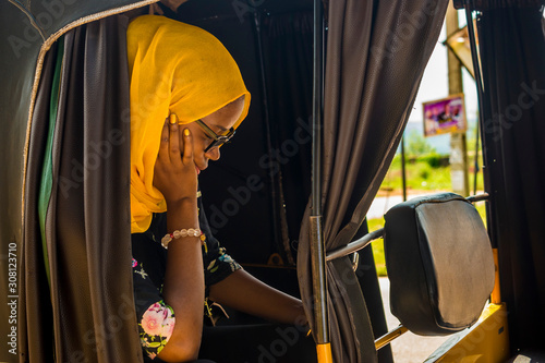 young african woman sitting alone in a rickshaw looking sad and tired photo