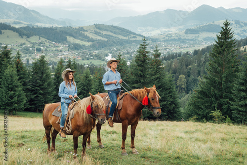 a couple horseback riding from overlooking wide open field and mountains © dvv1989