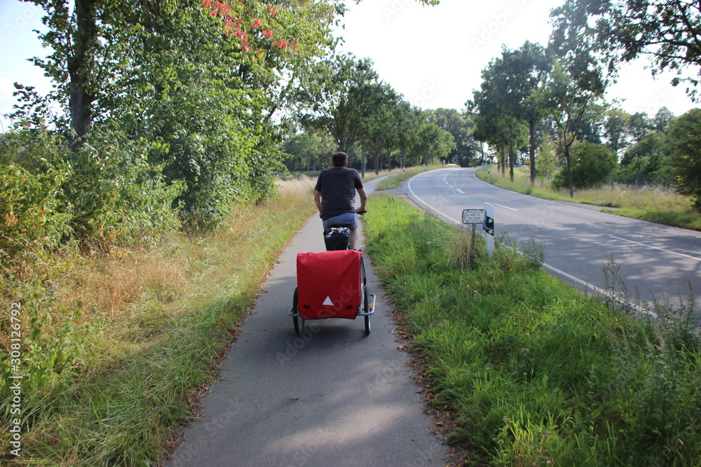 Man with child in bicycle trailer Man with child in bicycle trailer