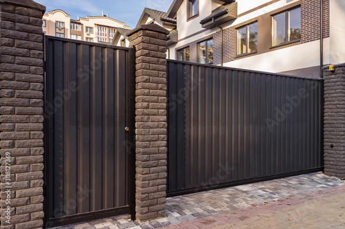Canvas Print Automatic metal gates with decorative brick columns on the street side