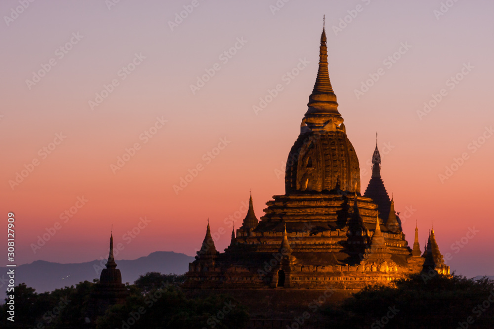 View on multiple pagoda during sunset, bathed in golden light and with some mountains in the background