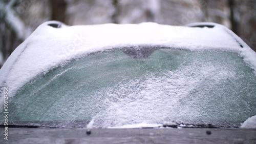 Windshield wipers brushing away snow and ice from a car's windshield