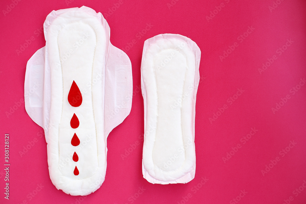 White woman cotton menstruation pads of different sizes with wings with red paper drops on pink background. White woman cotton menstruation pads of different sizes with wings with red paper drops on pink background.