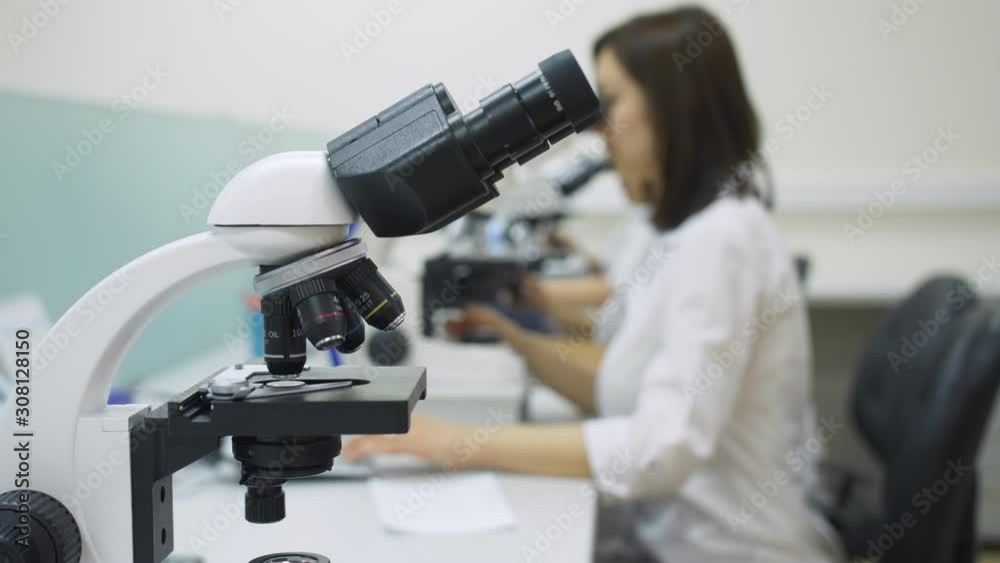 Laboratory Of Cytology. Microscope on a background of medical workers in lab coats in the laboratory. Laboratory Of Cytology. Microscope on a background of medical workers in lab coats in the laboratory.