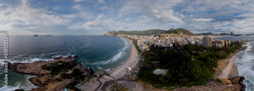 Rock formation on the Ipanema coast of Rio de Janeiro locally known as Arpoador, harpooner, with in the background the wider cityscape with the Corcovado mountain against a blue cloudy sky