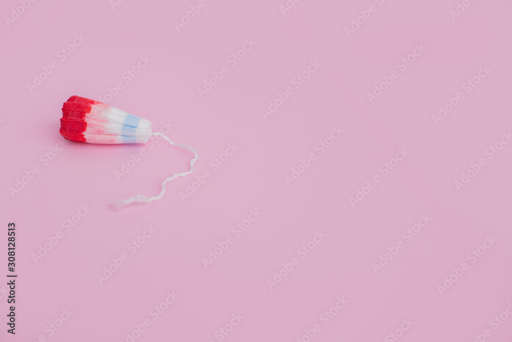 Female swab with a drop of red blood on a pink background Female swab with a drop of red blood on a pink background