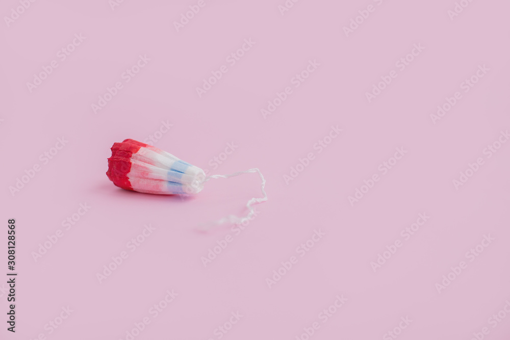 Female swab with a drop of red blood on a pink background Female swab with a drop of red blood on a pink background