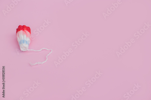 Female swab with a drop of red blood on a pink background
