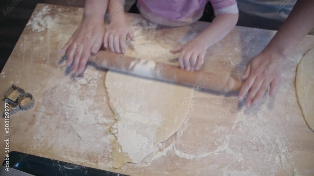 Little daughter helps mom in the kitchen with baking. Knead the dough together. Little daughter helps mom in the kitchen with baking. Knead the dough together.