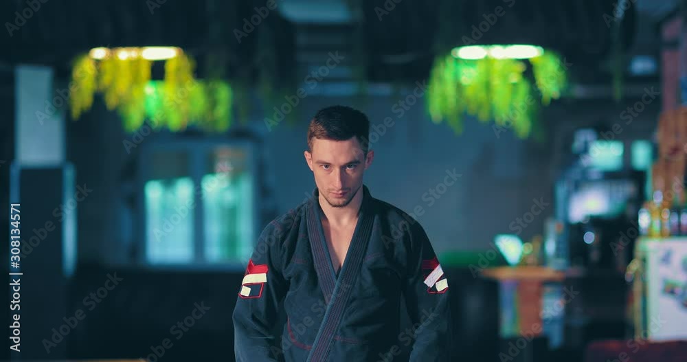 Judo fighter looks at the enemy before the fight, a serious menacing look. Portrait view. Judo fighter looks at the enemy before the fight, a serious menacing look. Portrait view.