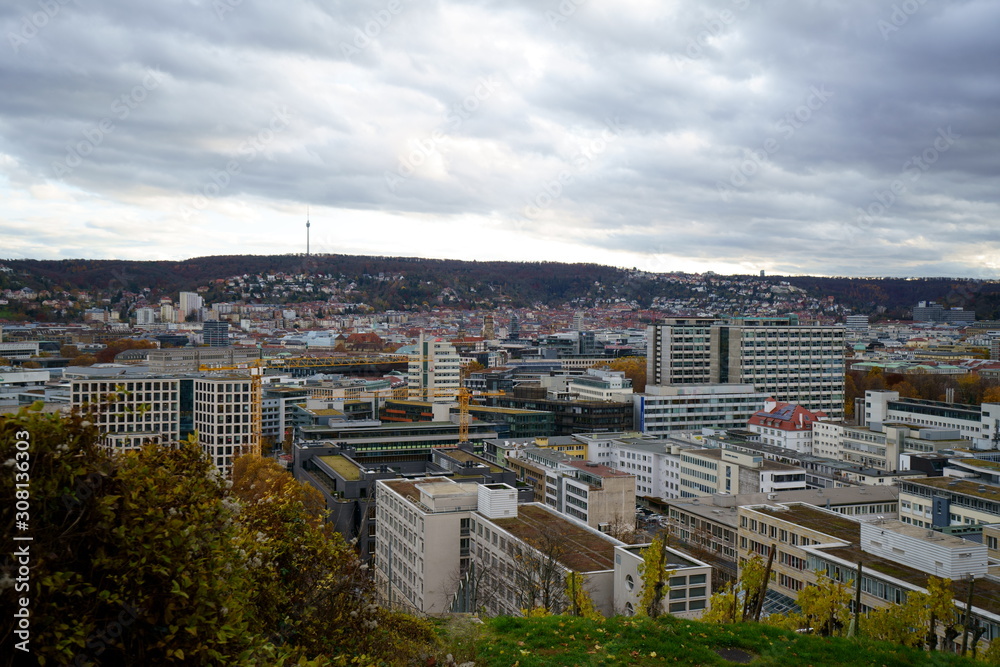 Germany, Houses of city stuttgart in valley surrounded by many hills and mountains forested with green trees in beautiful nature landscape