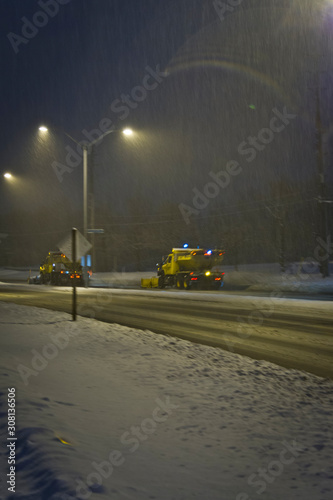 Snowplough driving on the street during a snowstorm at night in Toronto suburbs