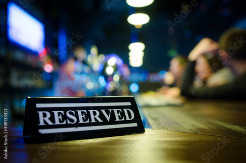 Restaurant reserved table sign standing on wooden table in bar