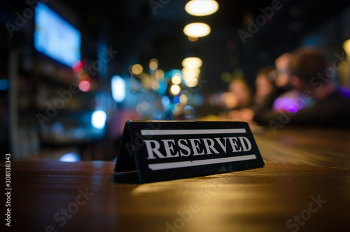Restaurant reserved table sign standing on wooden table in bar