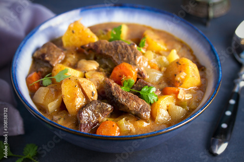 Beef meat stewed with potatoes, carrots and spices in bowl on dark gray background.  horizontal image © freeskyline