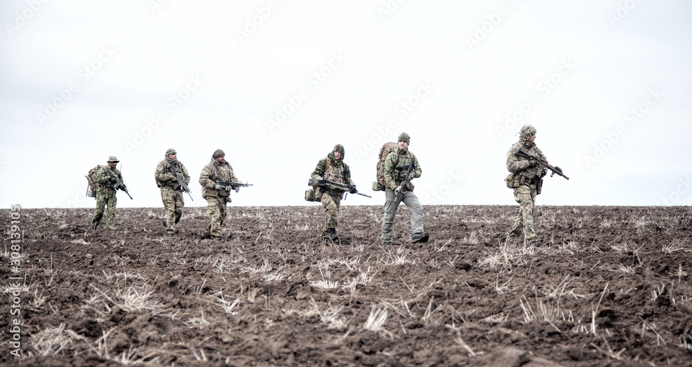 Army soldiers group on march in muddy field Army soldiers group on march in muddy field