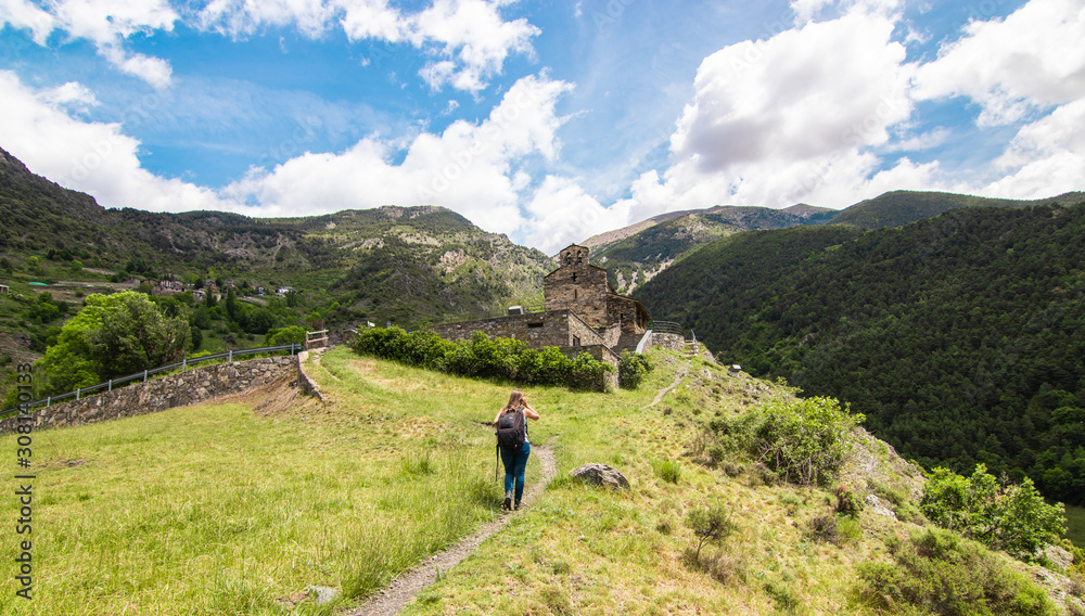 A young tourist woman during the hike in the Pyrenees mountains. On her way to the ancient church of Sant Serni de Nagol, located near Andorra La Vella, Andorra