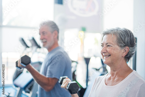 couple of two seniors training together at the gym with dumbbells in thei hand - heealthy and fitness lifestyle an concept - workout and weight lifting