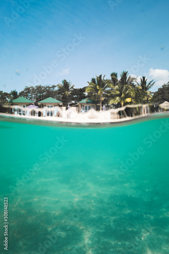 Small vacation island in group of Yasawa, Fiji, underwater view of crystal clear water and wooden cottages on a white sandy beach