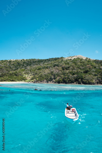 Yasawa islands, Fiji - 10/28/2019: Boat sailing towards the camera, from a small inhabited island in group of Yasawa, Fiji with crystal clear water