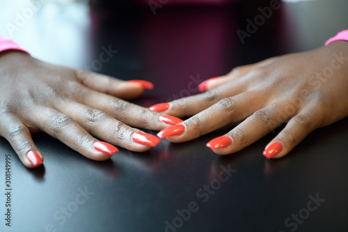 Open hands of a black woman with fingernails painted red on a black table
