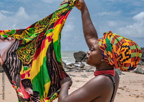 Ghana woman on the beautiful beach of Axim, located in Ghana West Africa. Headdress in traditional colors from Africa. photo