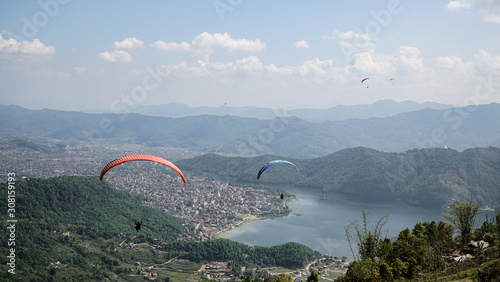 Paragliders flying against the Himalayas , Pokhara , Nepal.