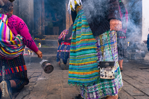 Las personas mayas están echando  incienso y encendiendo velas en la entrada de la Iglesia de Santo Tomas Chichicastenango Guatemala. photo