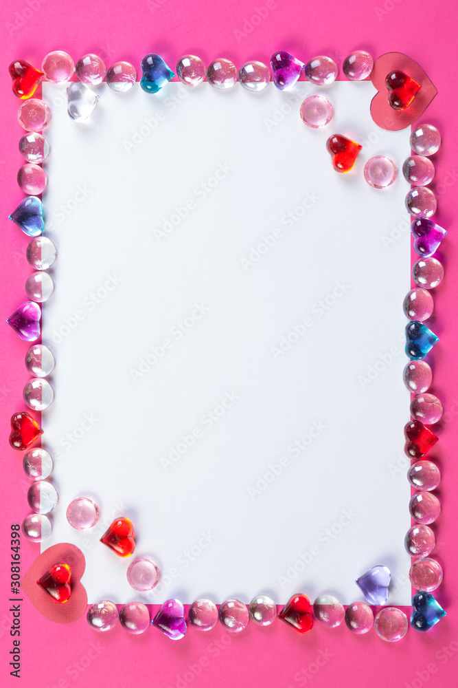 Obraz premium Valentine's day frame on pink background made of pebbles in the shape of a heart with white space and paper hearts.