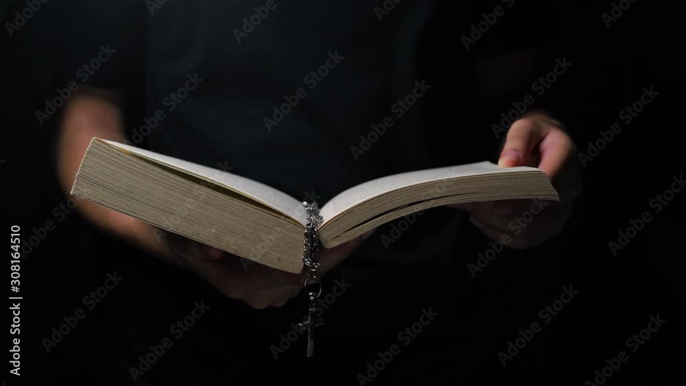 Christian woman opening and reading the holy bible with a cross. Slow backward dolly shot