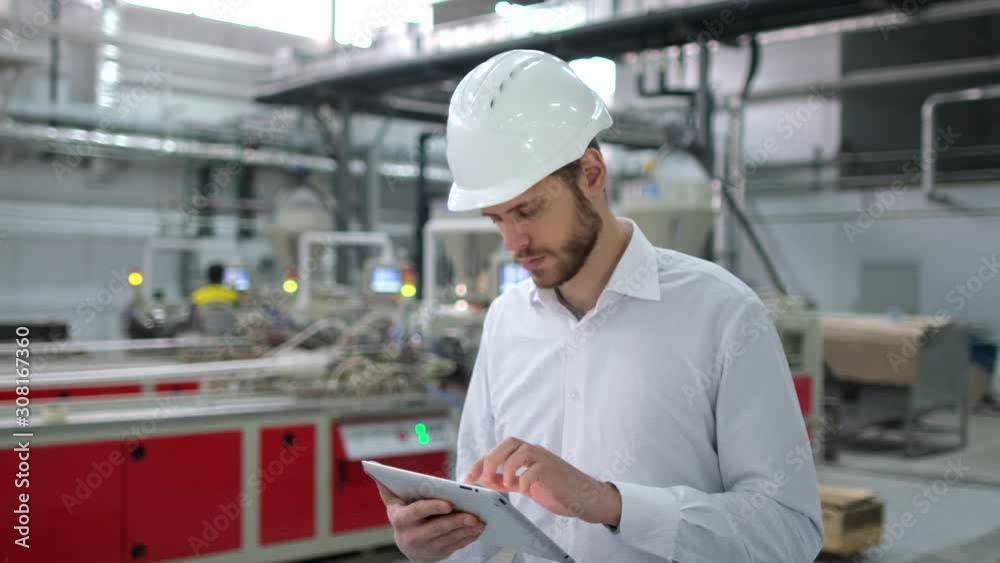 Caucasian bearded professional male engineer man people in hard hat working on engineering industrial manufacturing facility using tablet indoors, worker architect inspection contractor. slow-mo 4 K Caucasian bearded professional male engineer man people in hard hat working on engineering industrial manufacturing facility using tablet indoors, worker architect inspection contractor. slow-mo 4 K