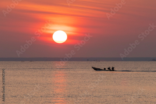 A pair of fishermen are riding a small local fishing boat to catch fish in the sea in the morning.