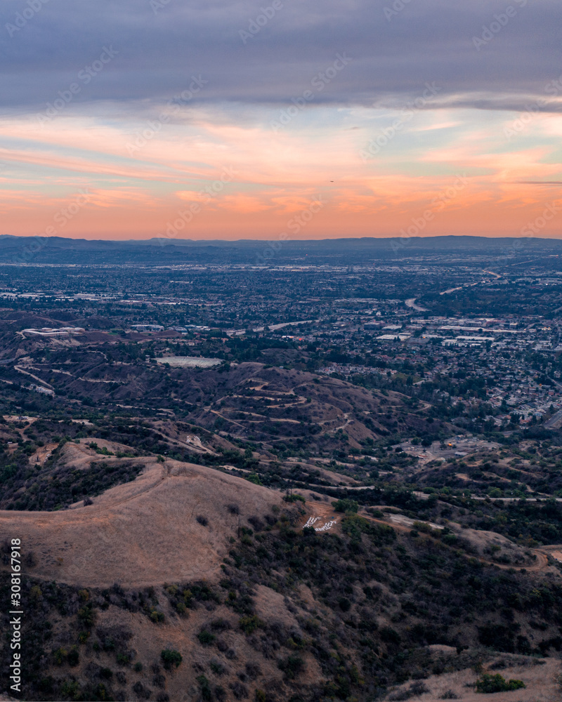 Aerial view of open rolling hills in suburban Southern California. Radio tower atop hill during sunset surrounded by mountains and ocean Aerial view of open rolling hills in suburban Southern California. Radio tower atop hill during sunset surrounded by mountains and ocean