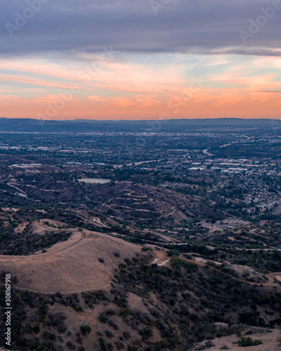 Aerial view of open rolling hills in suburban Southern California. Radio tower atop hill during sunset surrounded by mountains and ocean