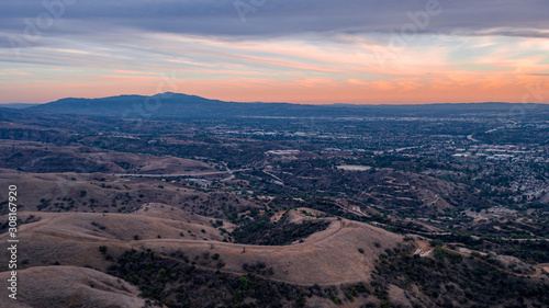 Aerial view of open rolling hills in suburban Southern California.  Radio tower atop hill during sunset surrounded by mountains and ocean photo
