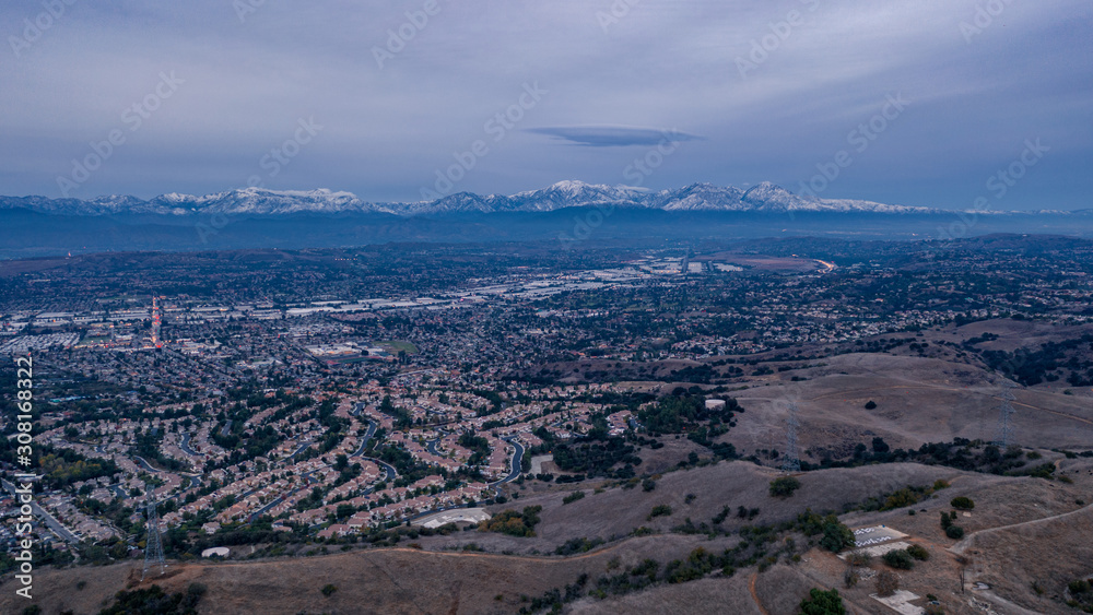 Aerial view of open rolling hills in suburban Southern California.  Radio tower atop hill during sunset surrounded by mountains and ocean