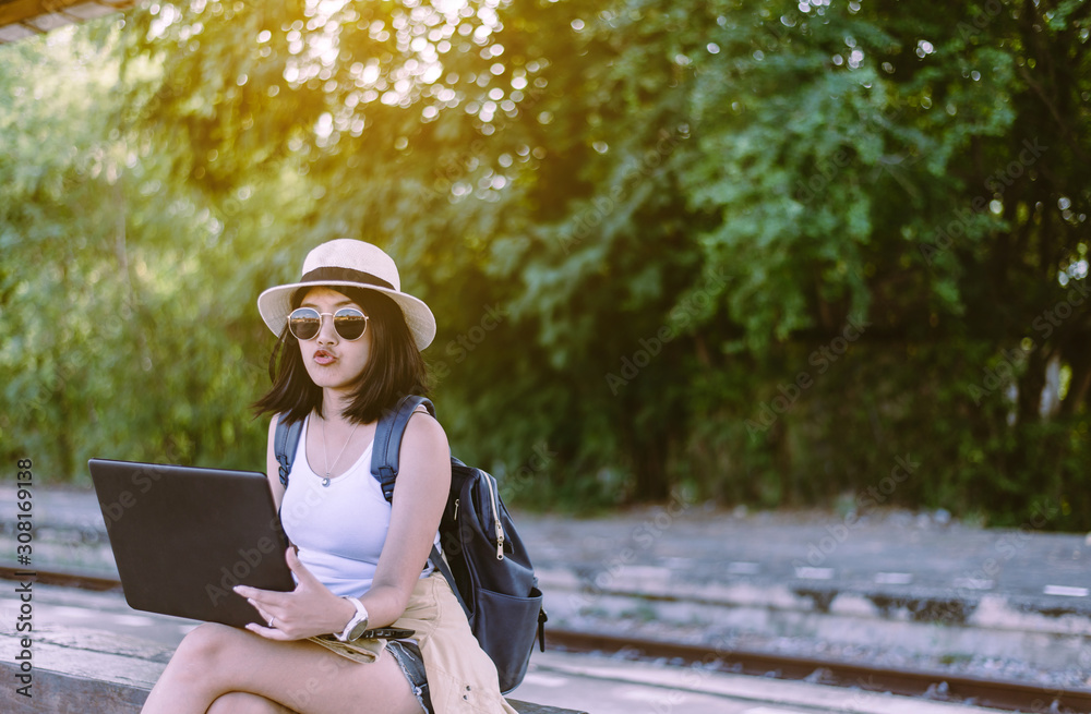Hipster asian woman tourist using internet with laptop computer and waiting train at train station,Travel and vacation concept Hipster asian woman tourist using internet with laptop computer and waiting train at train station,Travel and vacation concept