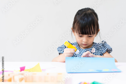 Adorable asian little girl is making do it yourself special gift happy birthday card for her father with happy moment, concept of creativity learning activity for kid development.