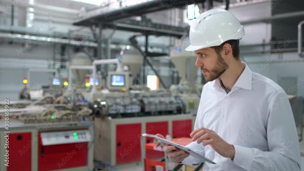 Caucasian bearded professional male engineer man people in hard hat working on engineering industrial manufacturing facility using tablet indoors, worker architect inspection contractor. slow-mo 4 K Caucasian bearded professional male engineer man people in hard hat working on engineering industrial manufacturing facility using tablet indoors, worker architect inspection contractor. slow-mo 4 K