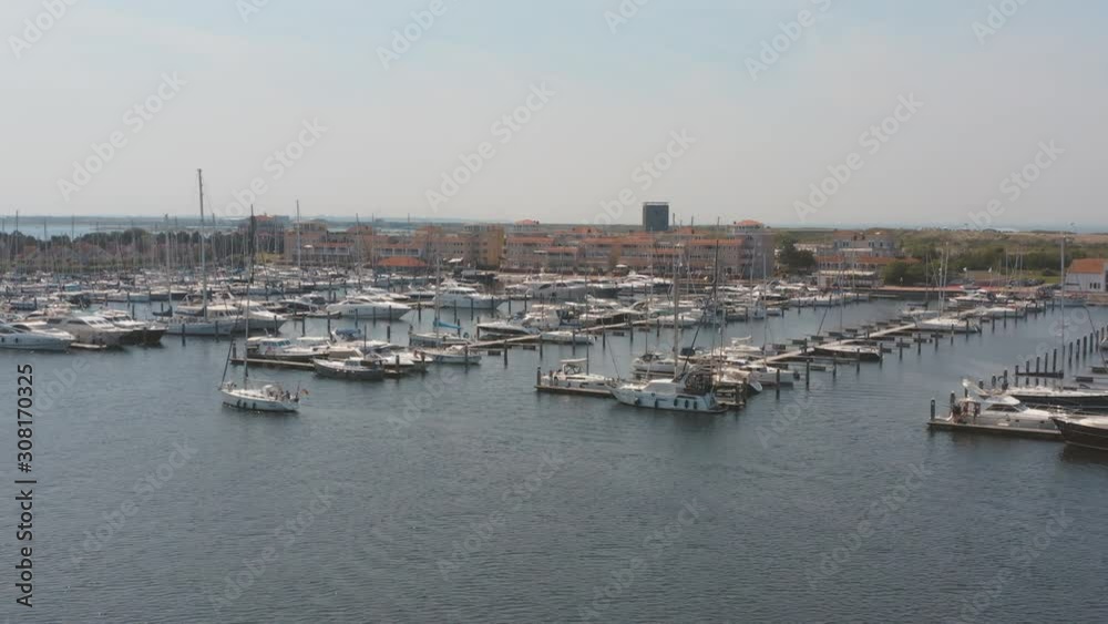 Cinematic drone / aerial panorama shot of a marina with sailing boats one boat sailing in the foreground on a sunny day at Zeeland at the north sea, Netherlands, 30p Cinematic drone / aerial panorama shot of a marina with sailing boats one boat sailing in the foreground on a sunny day at Zeeland at the north sea, Netherlands, 30p