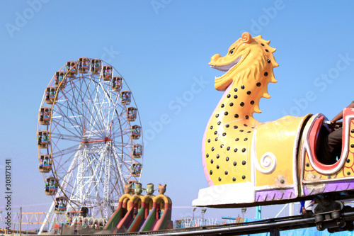 Fotografie Dragon train and giant ferries wheel in funfair, India.