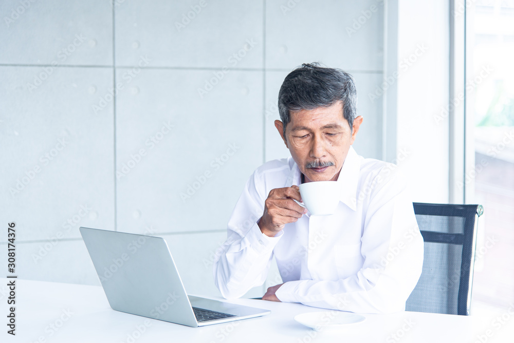 Asian Business old man with white shirt working and drinking coffee in the meeting room at the office Asian Business old man with white shirt working and drinking coffee in the meeting room at the office