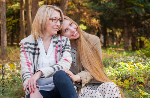 Friendly relations of an adult daughter and mother. Happy family, young woman hugs her mom in park