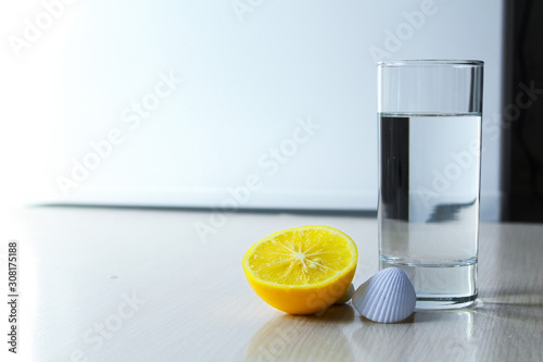 a glass of water and lemon stands on the table.