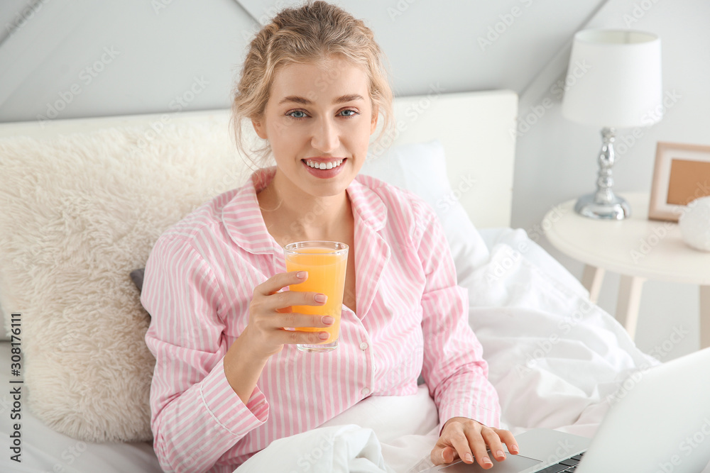 Morning of beautiful young woman with laptop drinking juice in bed Morning of beautiful young woman with laptop drinking juice in bed