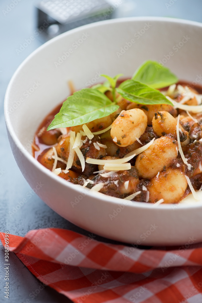 Close-up of italian gnocchi cooked with tomato sauce, spinach and cheese, selective focus, vertical shot Close-up of italian gnocchi cooked with tomato sauce, spinach and cheese, selective focus, vertical shot